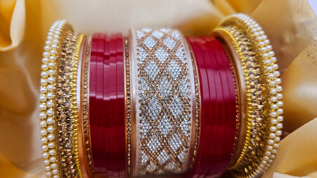 Close-up of red and gold bangles with intricate patterns on a beige fabric background