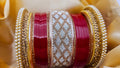 Close-up of red and gold bangles with intricate patterns on a beige fabric background